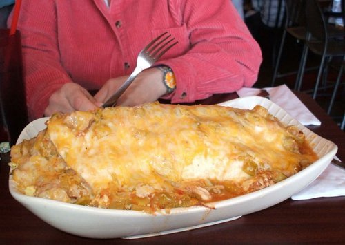Giant Breakfast Burrito A seven pound breakfast burrito stuffed with potatoes, eggs, onions, and ham bits, lots of cheese on top and smothered in red chile. (via dogsarefunyes)
